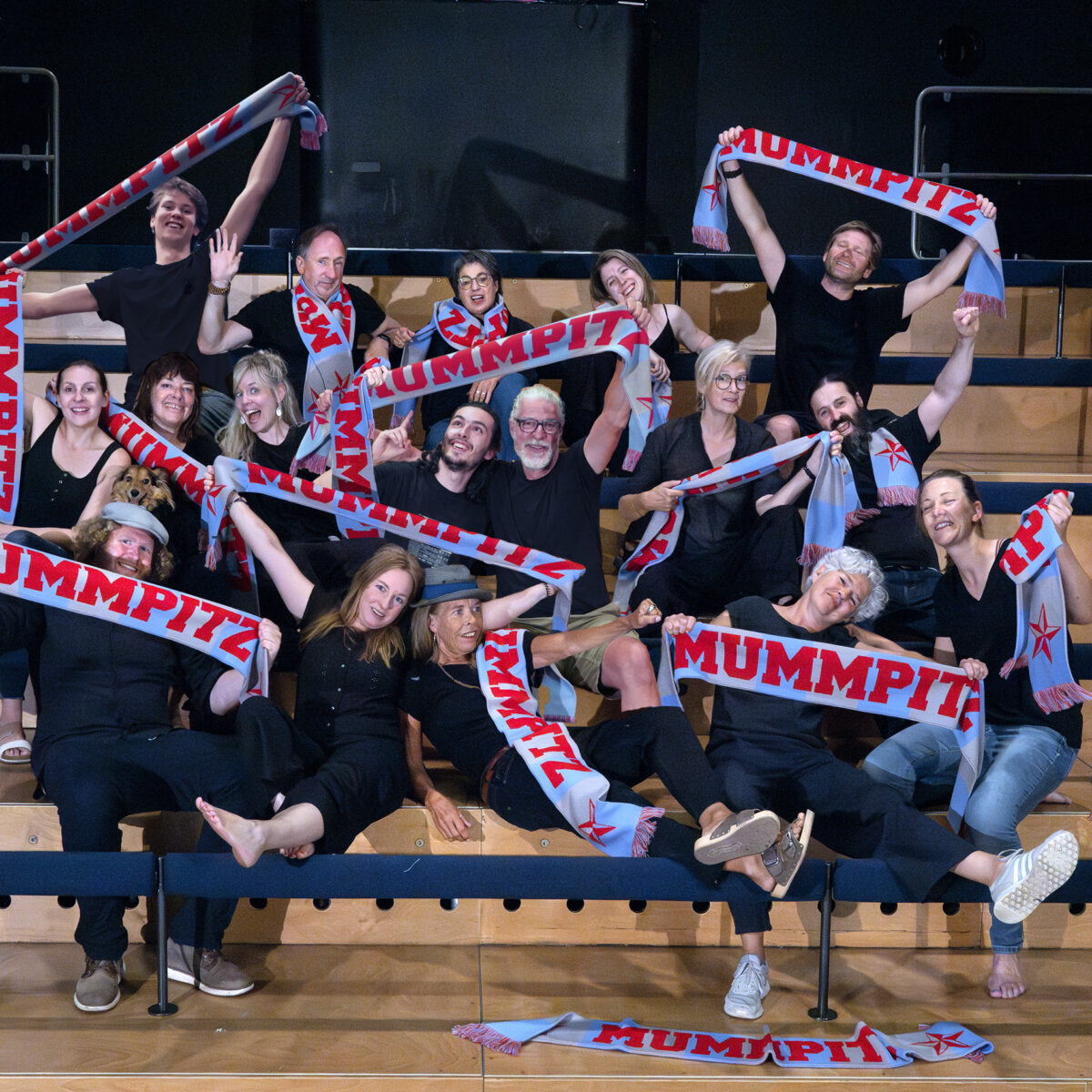 Das Ensemble des Theater Mummpitz auf der Saaltribüne mit Fanschals des Theater Mummpitz