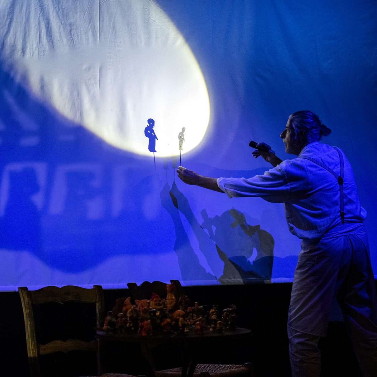 Spieler hält eine Taschenlampe und macht ein Schattenbild auf eine blaue Leinwand